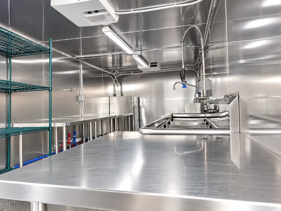 Stainless worktable, pre-rinse faucet and sinks inside a 22 to 26 foot low-temperature dishwashing trailer